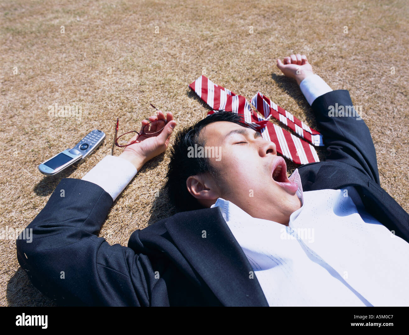 Asian Businessman lying flat on the ground Stock Photo Alamy