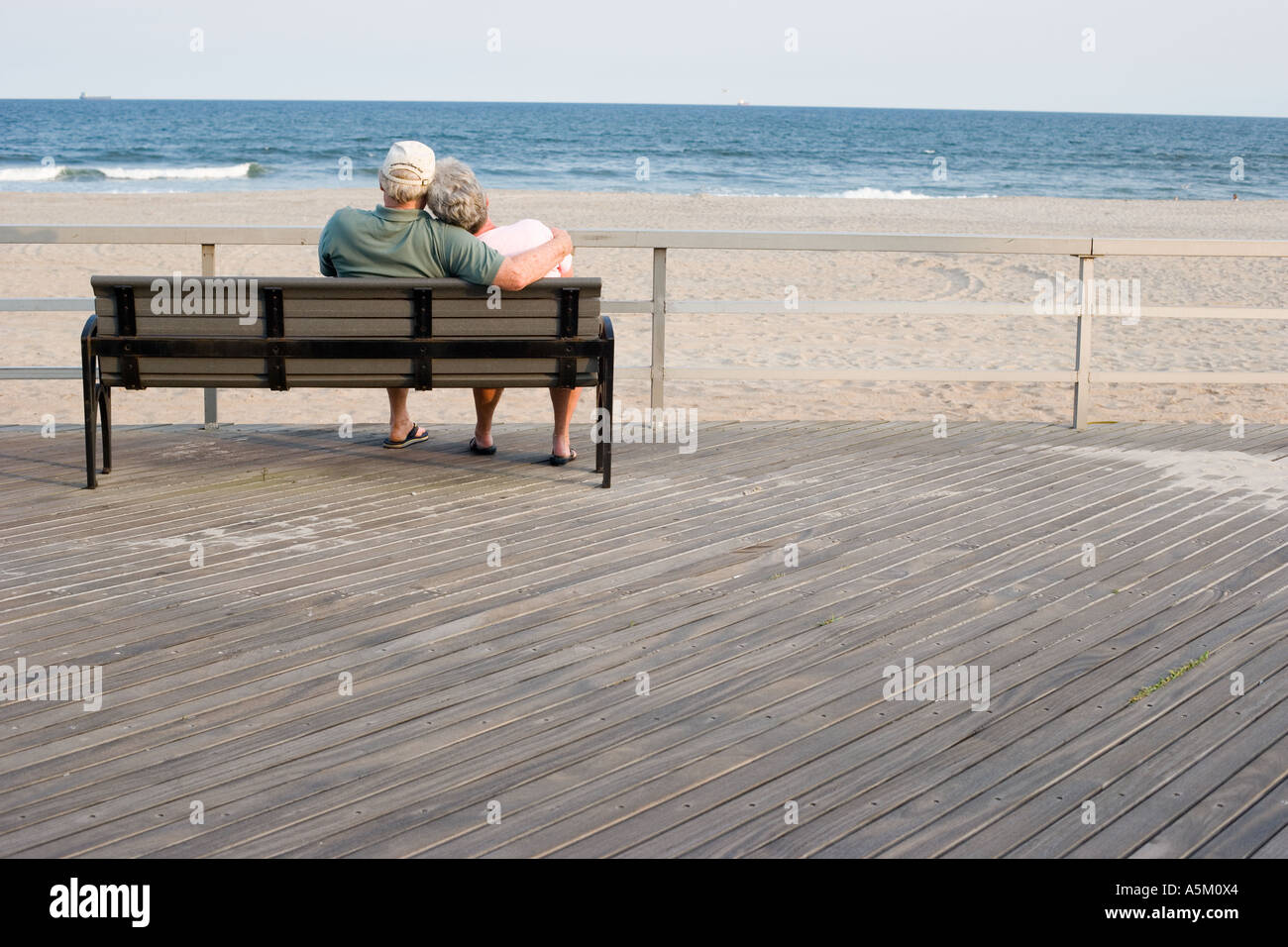 Senior couple relaxing on a park bench by the sea Stock Photo