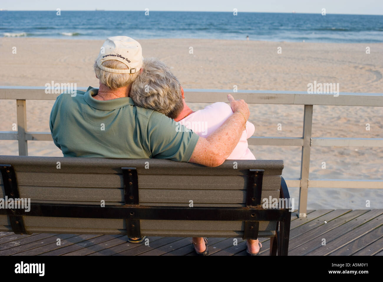 Senior couple relaxing on a park bench by the sea Stock Photo