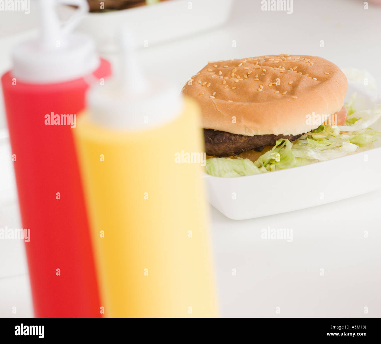 Close up of hamburger and condiment bottles Stock Photo