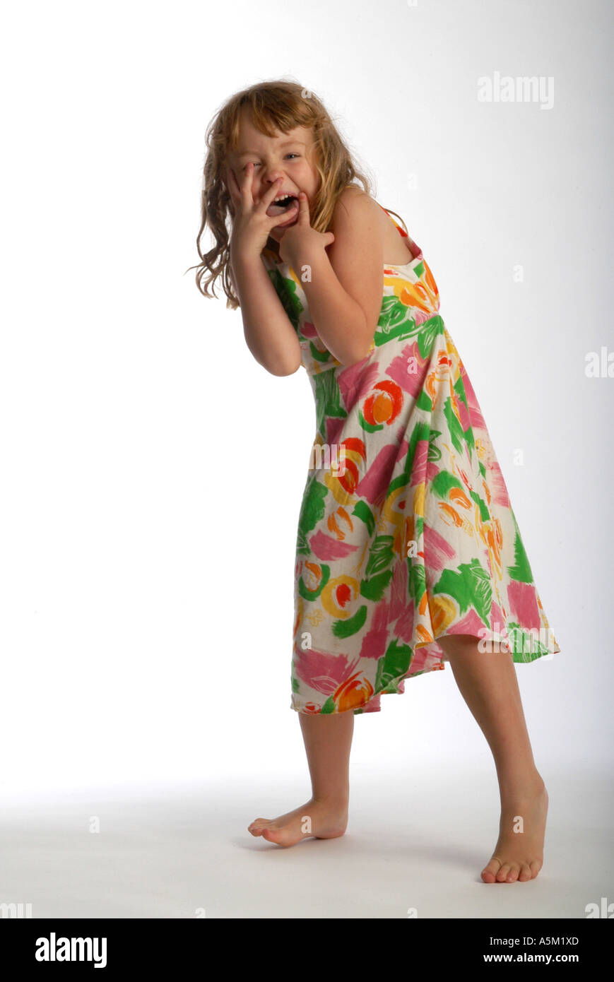 A five year old girl wearing a colorful dress is frozen in action as she dances expressively Stock Photo