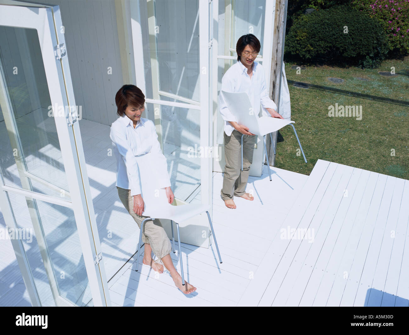 Asian couple carrying chairs to the porch Stock Photo