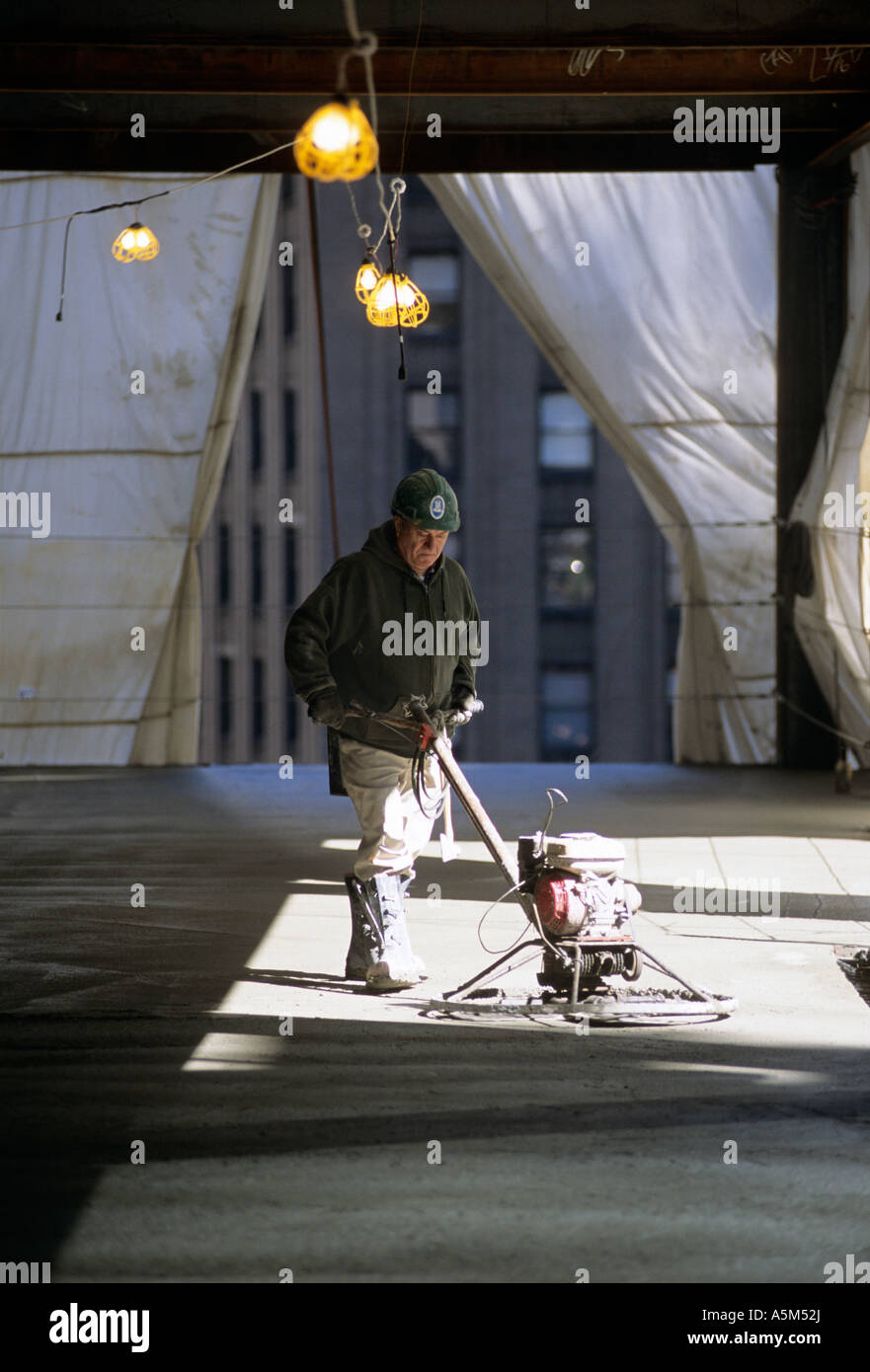 Worker Smoothing Newly Poured Concrete Floor On Random House