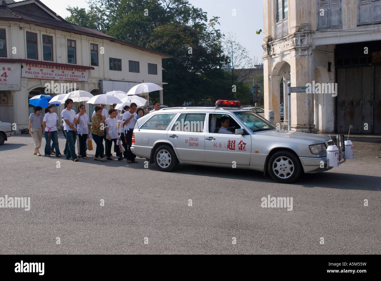 A Chinese funeral procession walking behind a hearse in Ipoh Malaysia Stock Photo