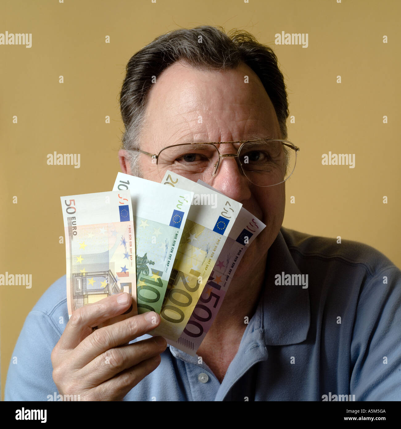 MR MATURE MAN HOLDING EURO BANKNOTES IN FRONT OF HIS FACE Stock Photo