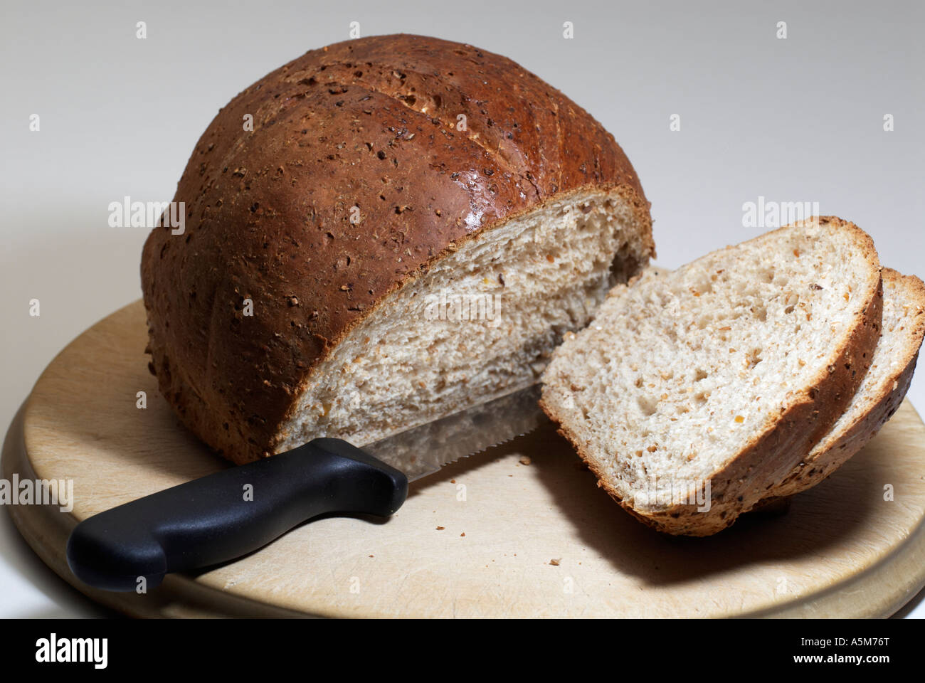 Freshly sliced round wheaten loaf on wooden 'bread board' with 'bread knife' Stock Photo