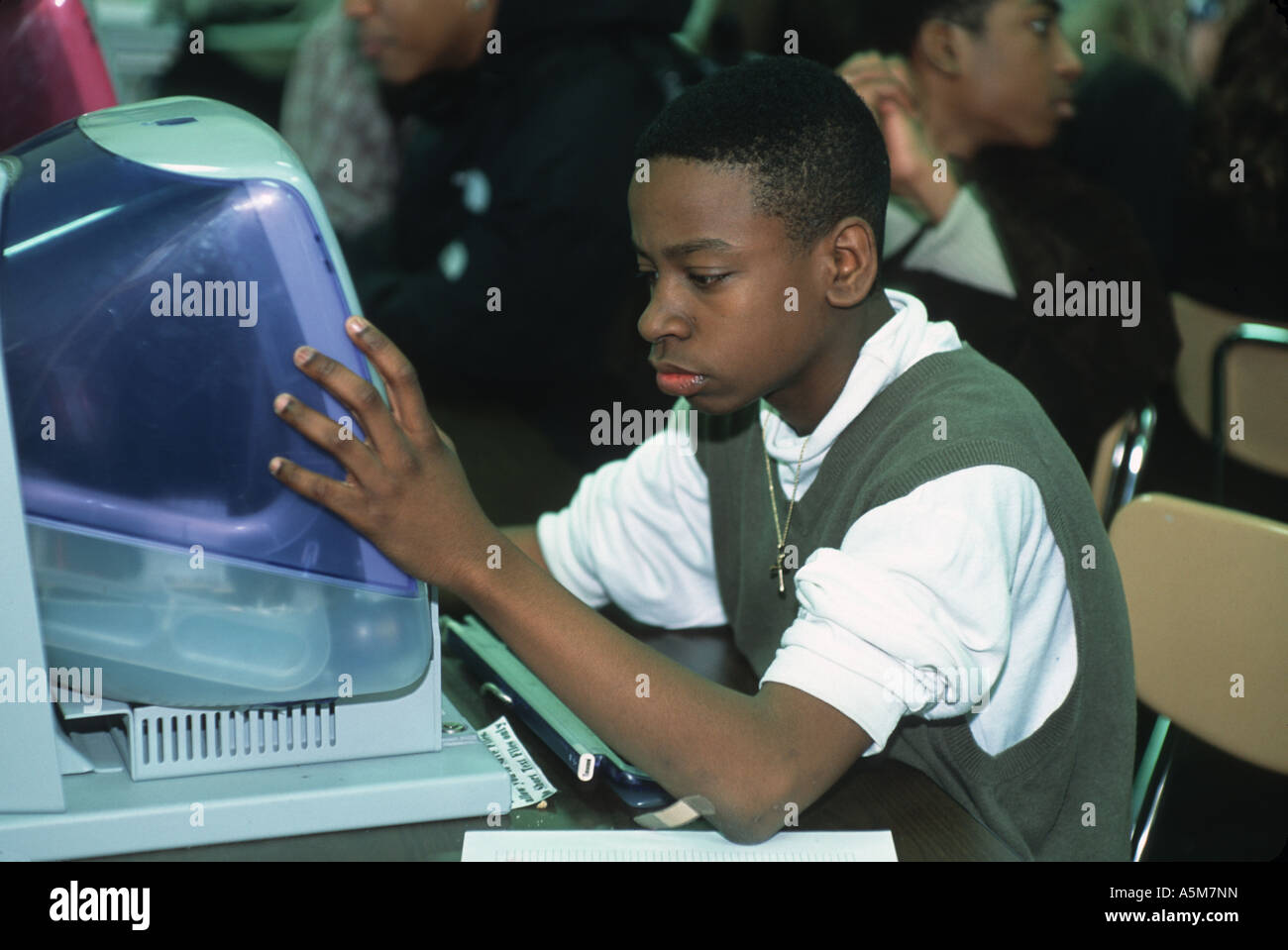 High school student works at computer doing homework at school library ...