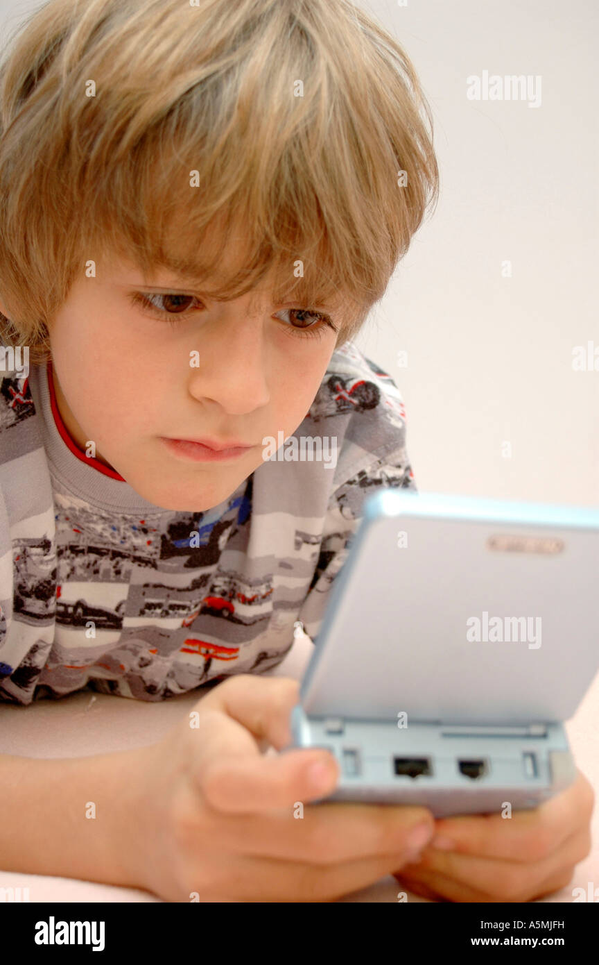 Junge spielt am Gameboy boy playing with Gameboy Kind Menschen Mensch Personen Leute people jung kindlich Kinder Kindheit child Stock Photo