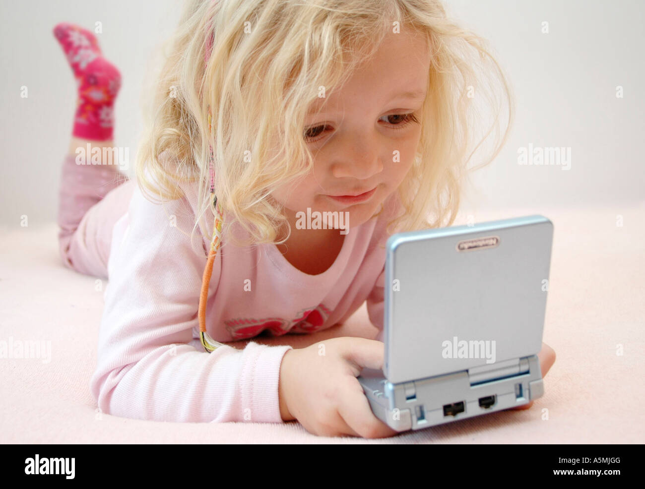 4 jähriges Mädchen spielt mit Gameboy four years old girl playing with Gameboy Kind Menschen Mensch Personen Leute people jung k Stock Photo