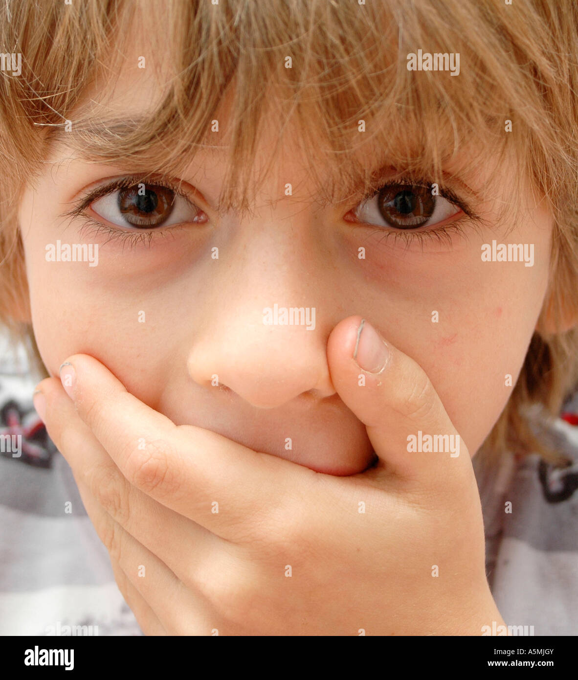 Erstaunter Junge hält sich die Hand vor den Mund amazed boy Kind Menschen Mensch Personen Leute people jung kindlich Kinder Kind Stock Photo