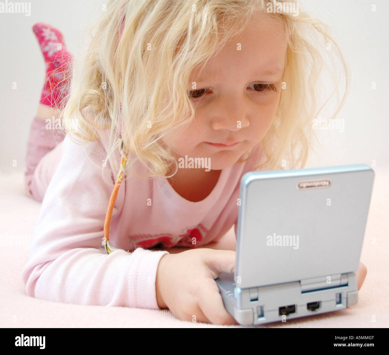 4 jähriges Mädchen spielt mit Gameboy four years old girl playing with Gameboy Kind Menschen Mensch Personen Leute people jung k Stock Photo