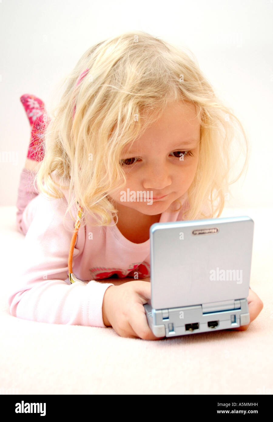 4 jähriges Mädchen spielt mit Gameboy four years old girl playing with Gameboy Kind Menschen Mensch Personen Leute people jung k Stock Photo