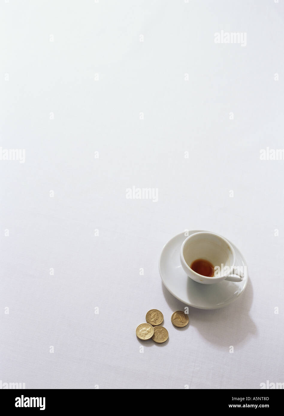 An empty cup of coffee and coins on table Stock Photo