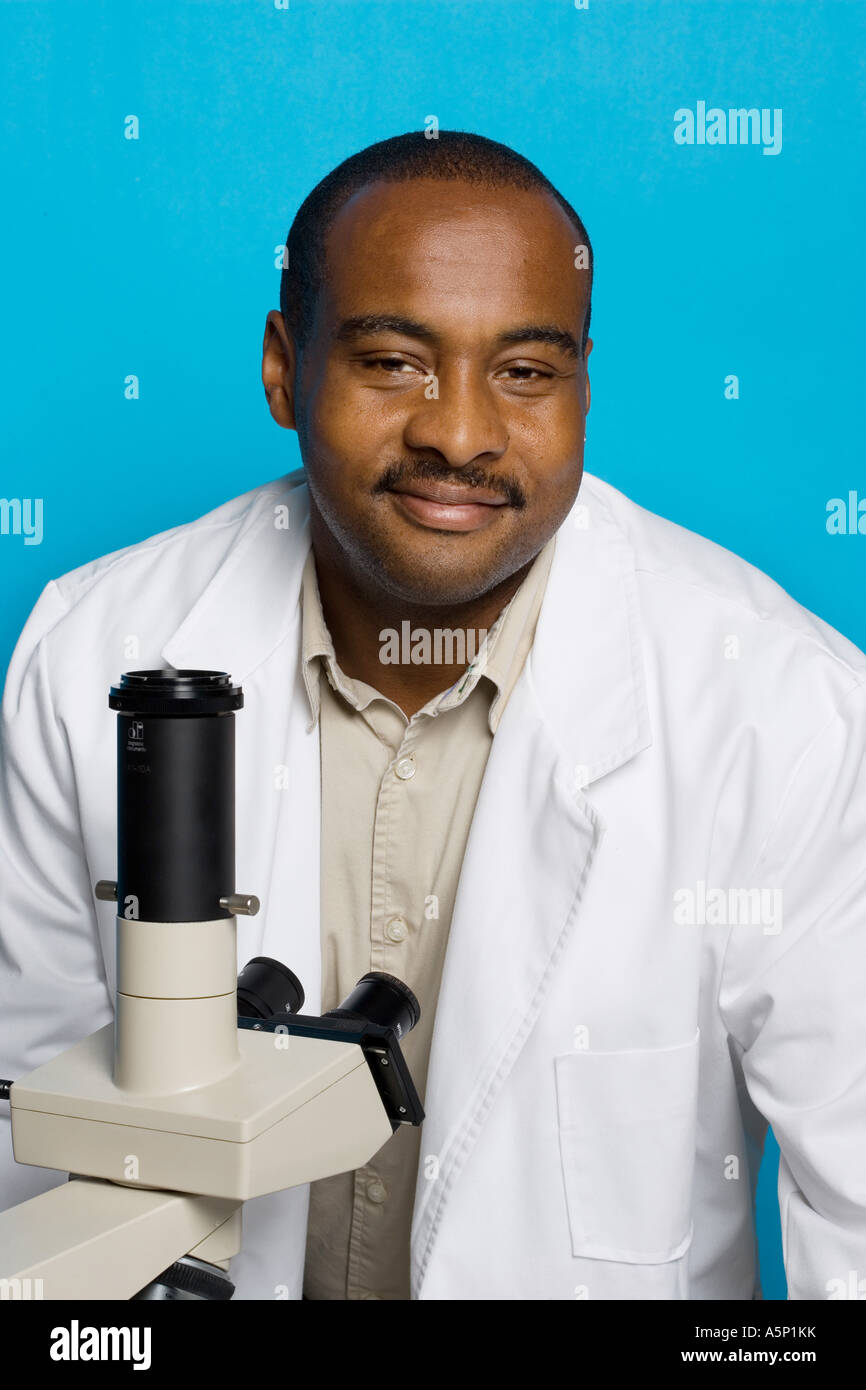 Third world researcher or medical tech (played by a model) with his microscope. Stock Photo