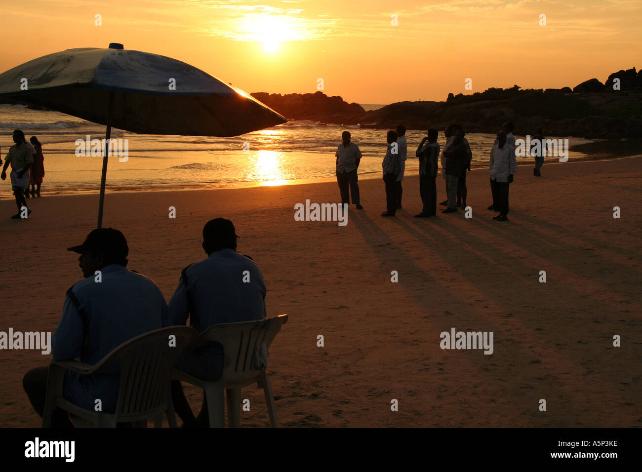 Men on the beach at sunset, Kovalam, southern india. Stock Photo