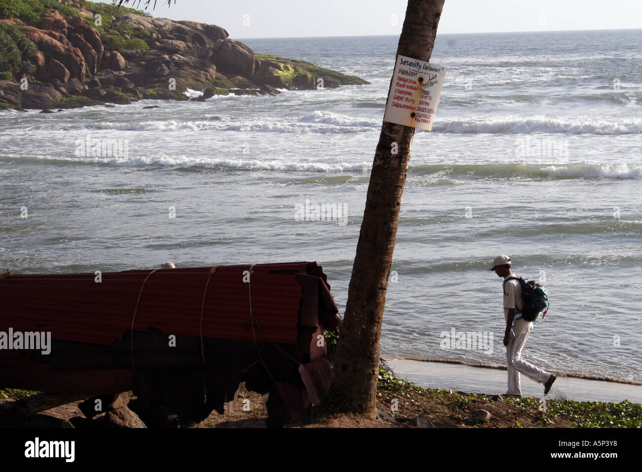 Local man walking alone across Kovalam lighthouse Beach, Kerela, India Stock Photo