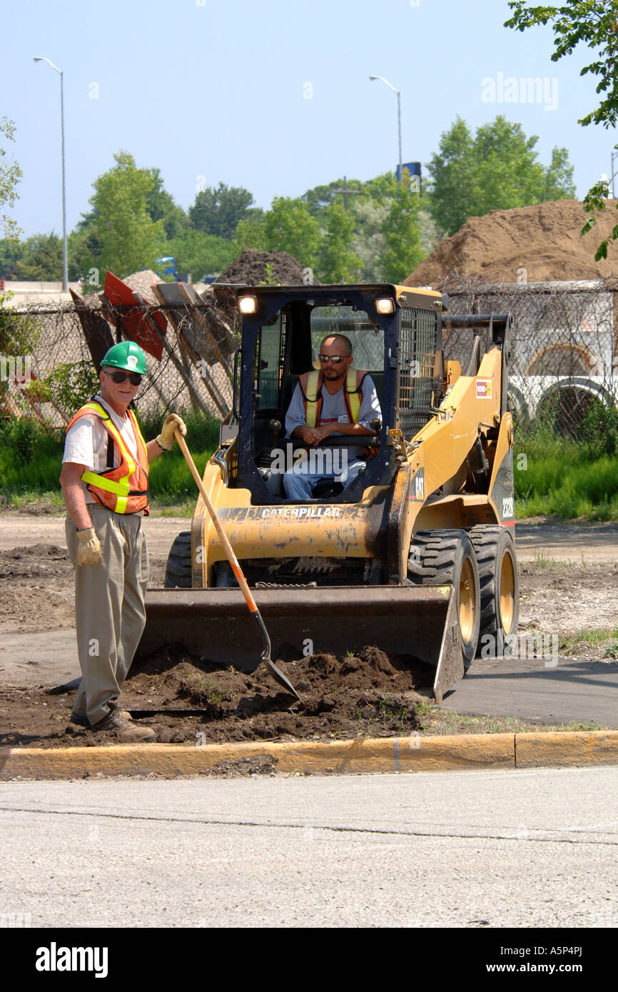 Construction workers using a bobcat mini tractor at a new development site in Michigan Stock Photo