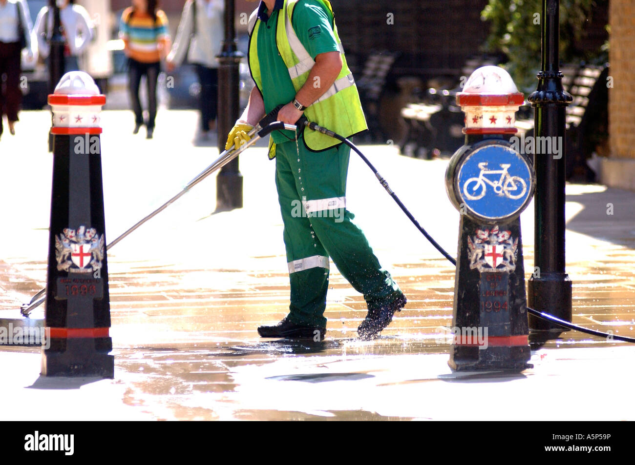 British council worker cleaning London street UK with pressure hose removing chewing gum from pavement Stock Photo