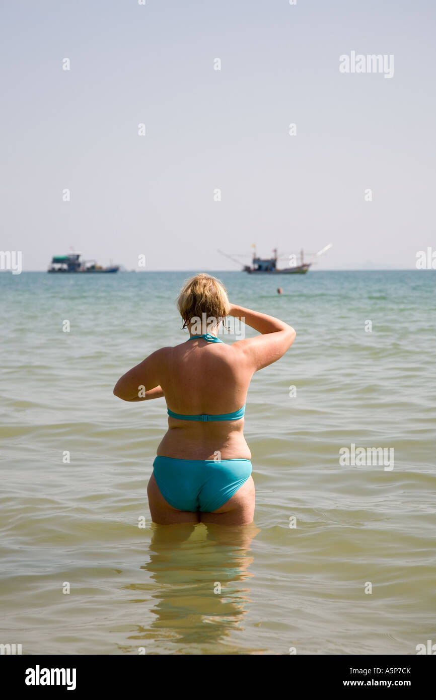 Middle aged european woman standing whilst watching or looking out seaward Krabi beach resort Andaman sea province Thailand Stock Photo