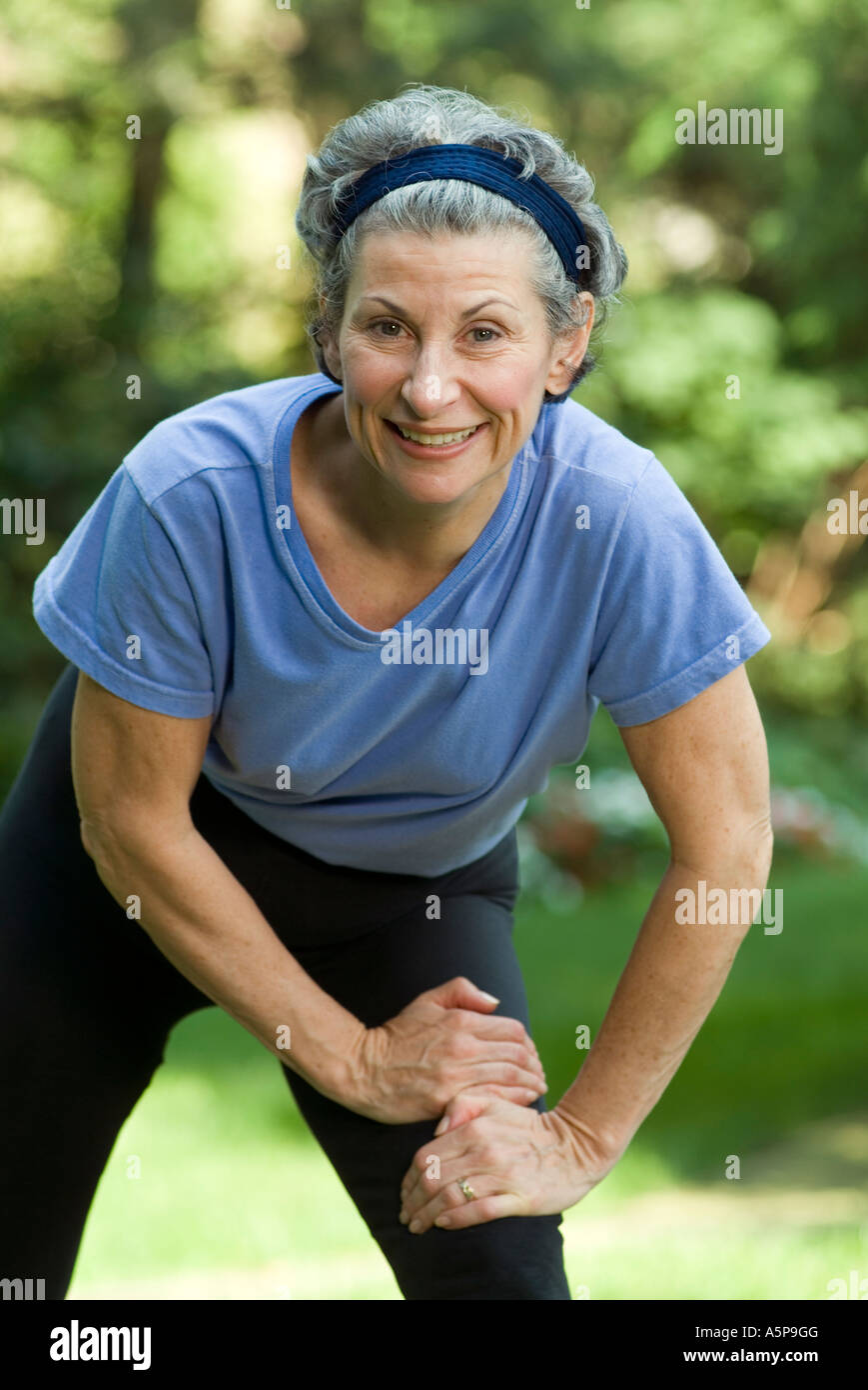 Older woman pausing while exercising outdoors. Stock Photo