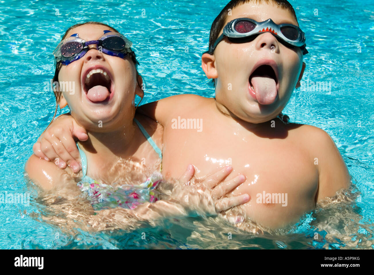 Boy and girl laughing and playing in swimming pool. Stock Photo