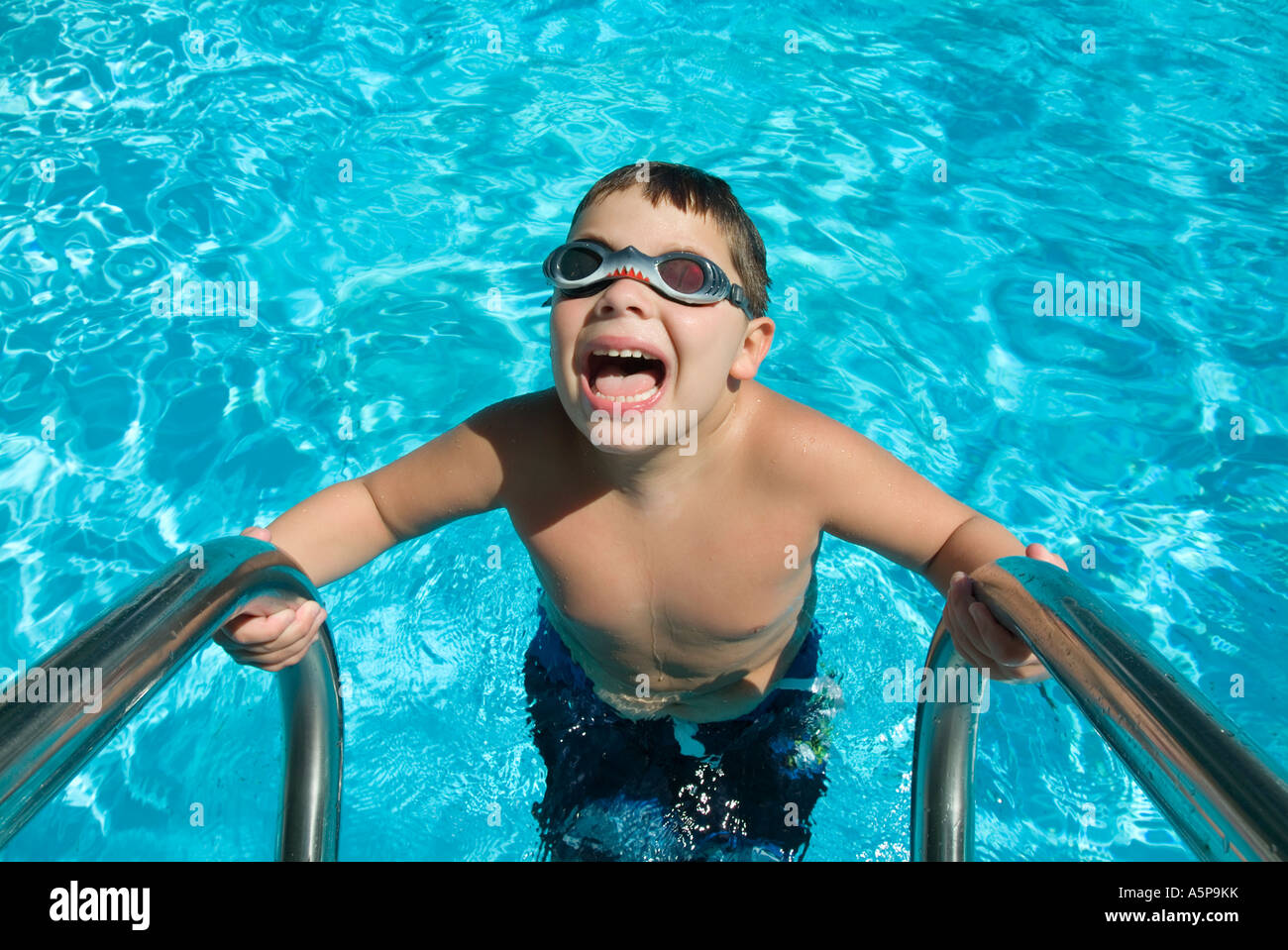 Boy with goggles laughing and playing in swimming pool. Stock Photo