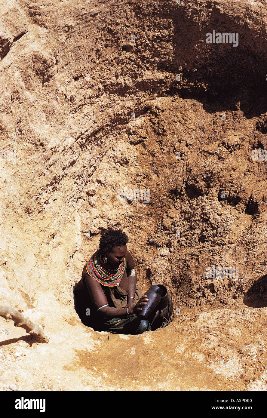 Turkana woman baling water into gourds at the bottom of a deep well Serolevi northern Kenya East Africa Stock Photo