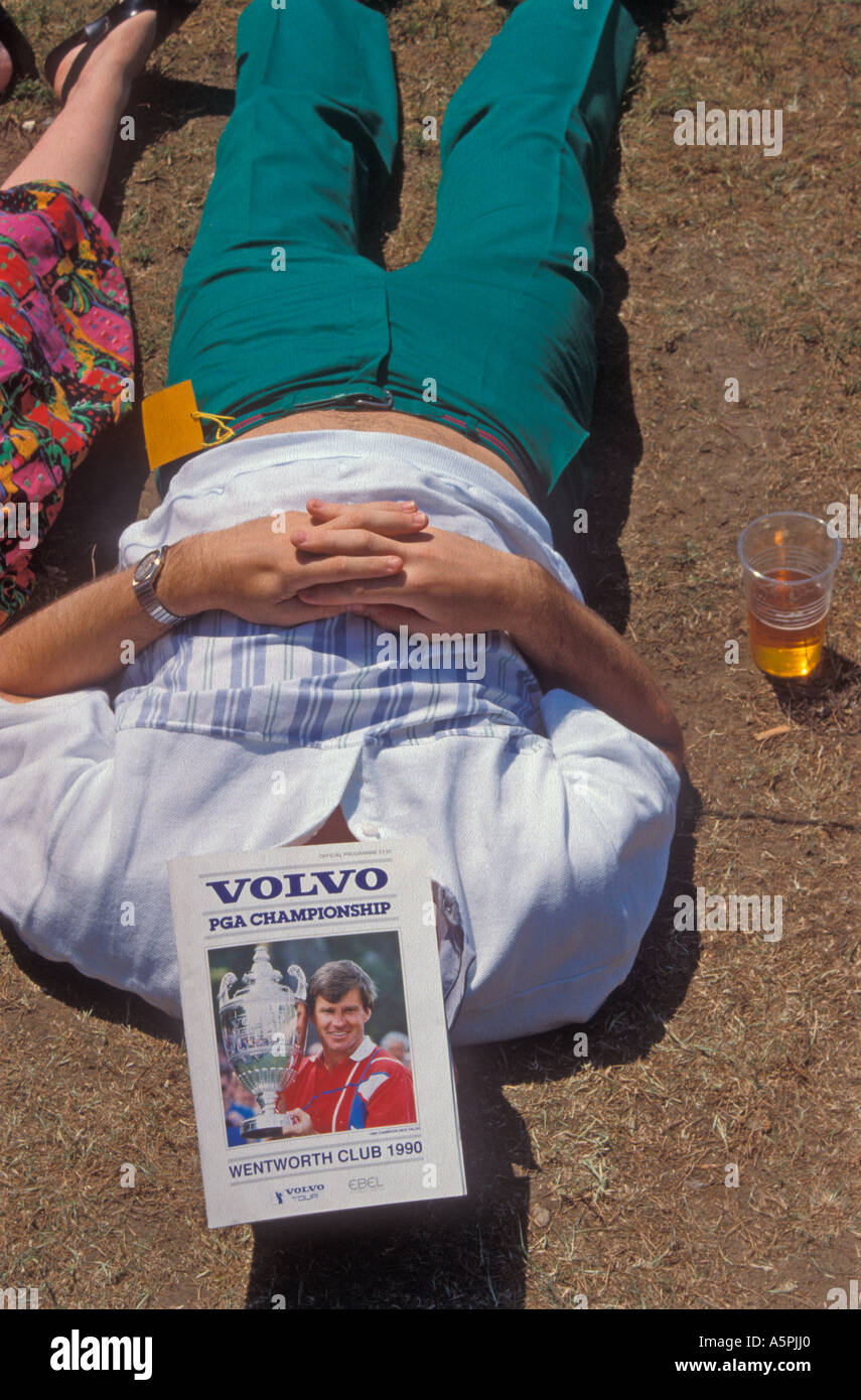 A golf fan at the Volvo PGA Championship, Wentworth, 1990, sunbathing with the official programme shielding his face. Stock Photo