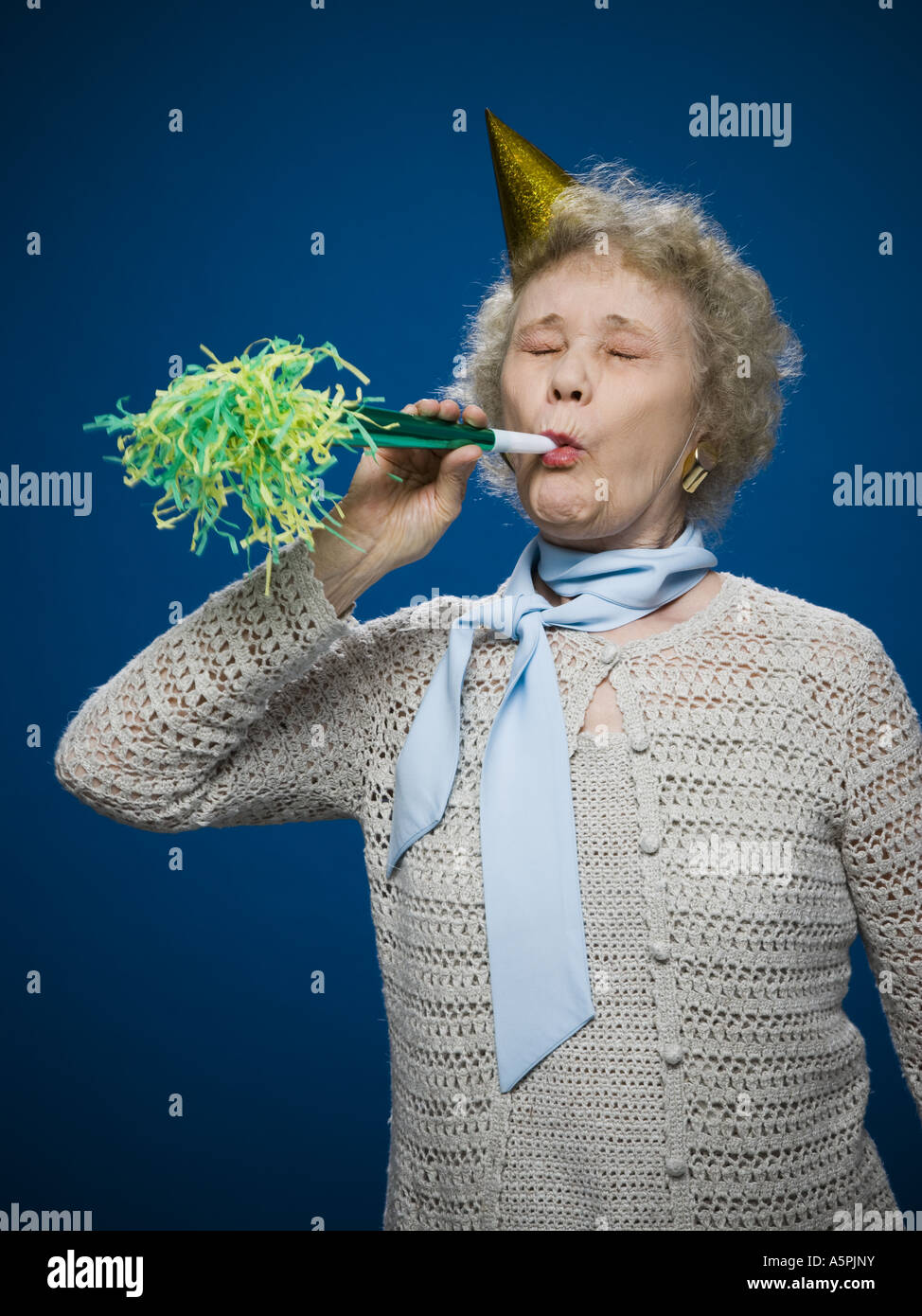 Older woman with noisemaker and party hat Stock Photo Alamy