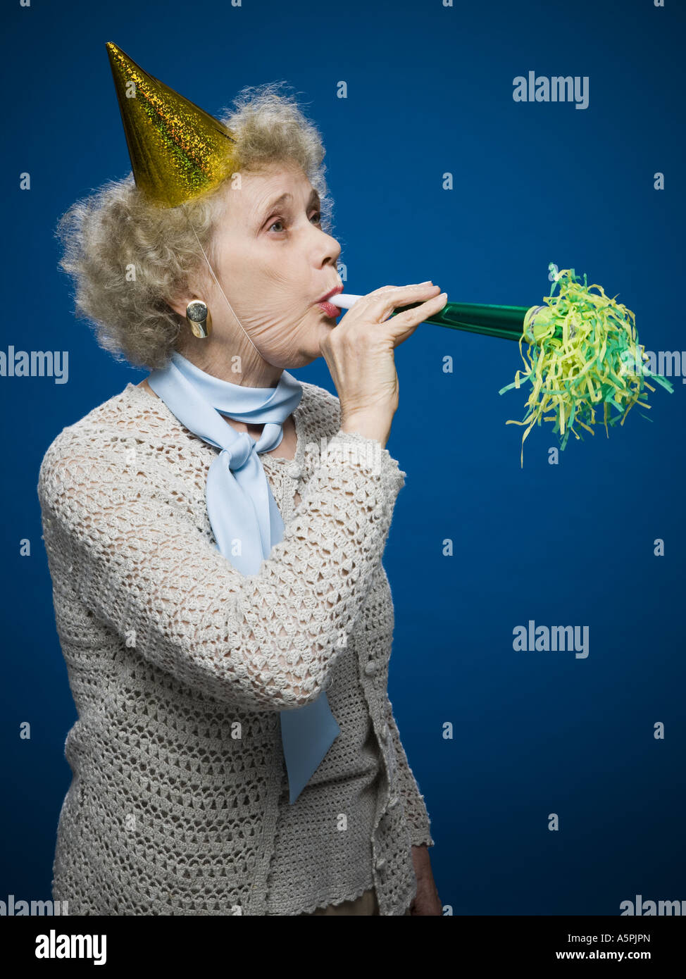 Older woman with noisemaker and party hat Stock Photo Alamy