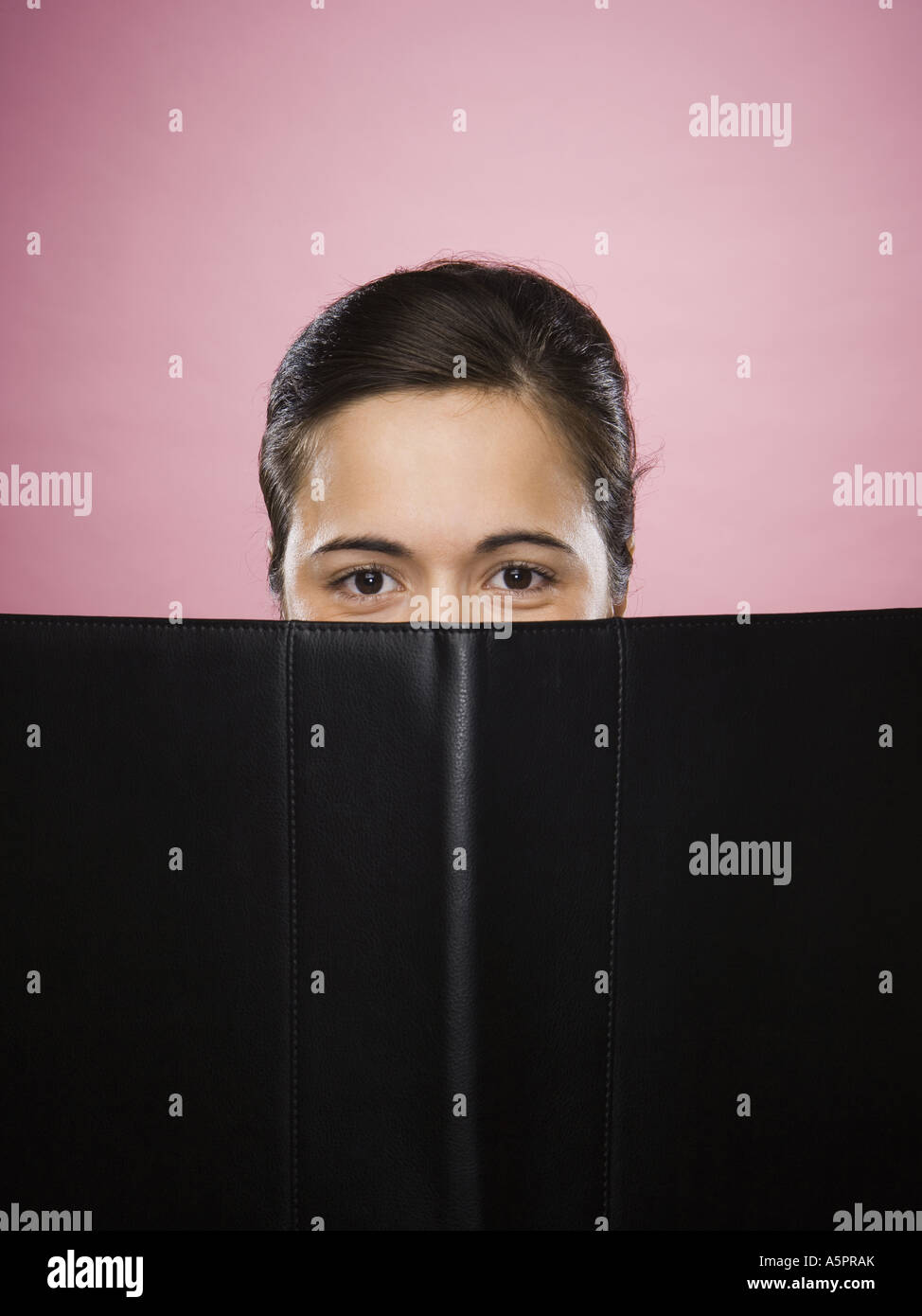 Close-up of a young woman's face partially hidden with a file Stock Photo