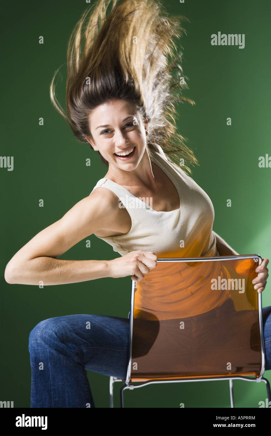 Woman sitting backwards on chair and tossing hair Stock Photo Alamy