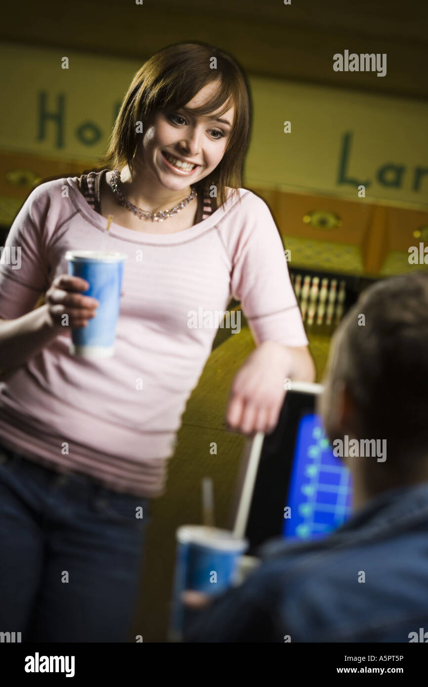 Teenage girl holding a disposable glass of cola and looking at a young man Stock Photo