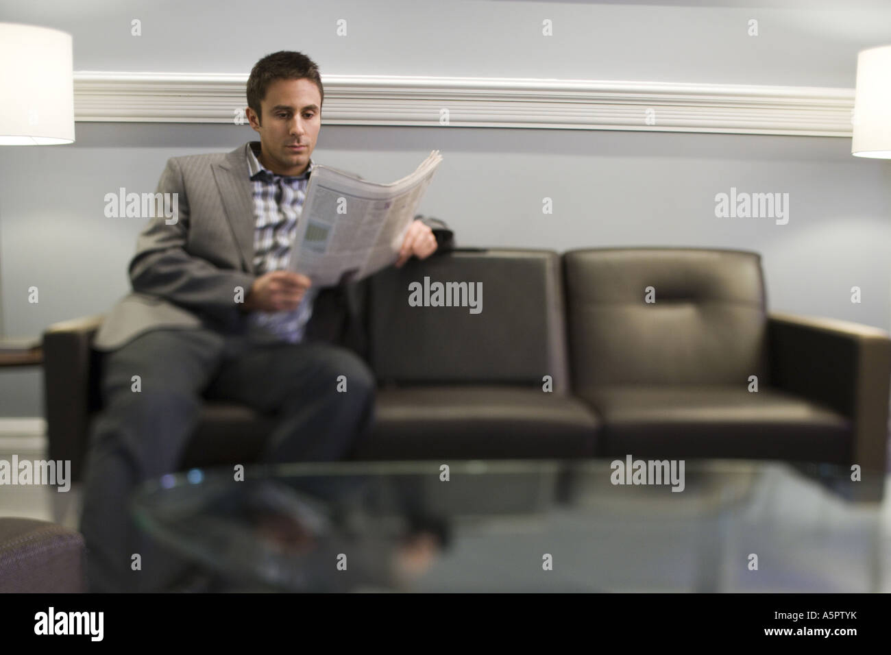 Businessman sitting on a couch and reading a newspaper Stock Photo - Alamy