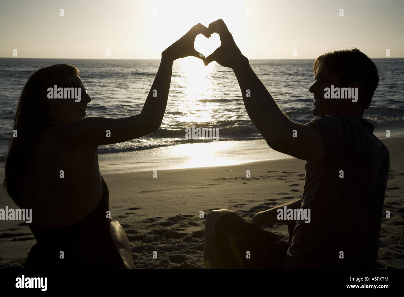 Couple on a beach making a heart symbol with their hands Stock Photo ...