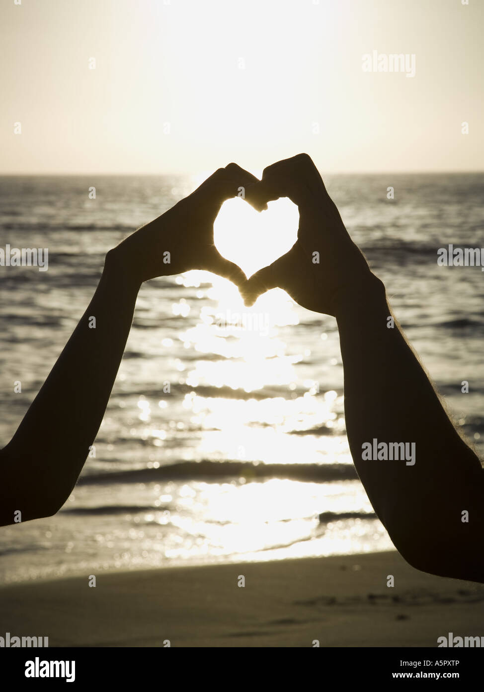Couple on a beach making a heart symbol with their hands Stock Photo ...