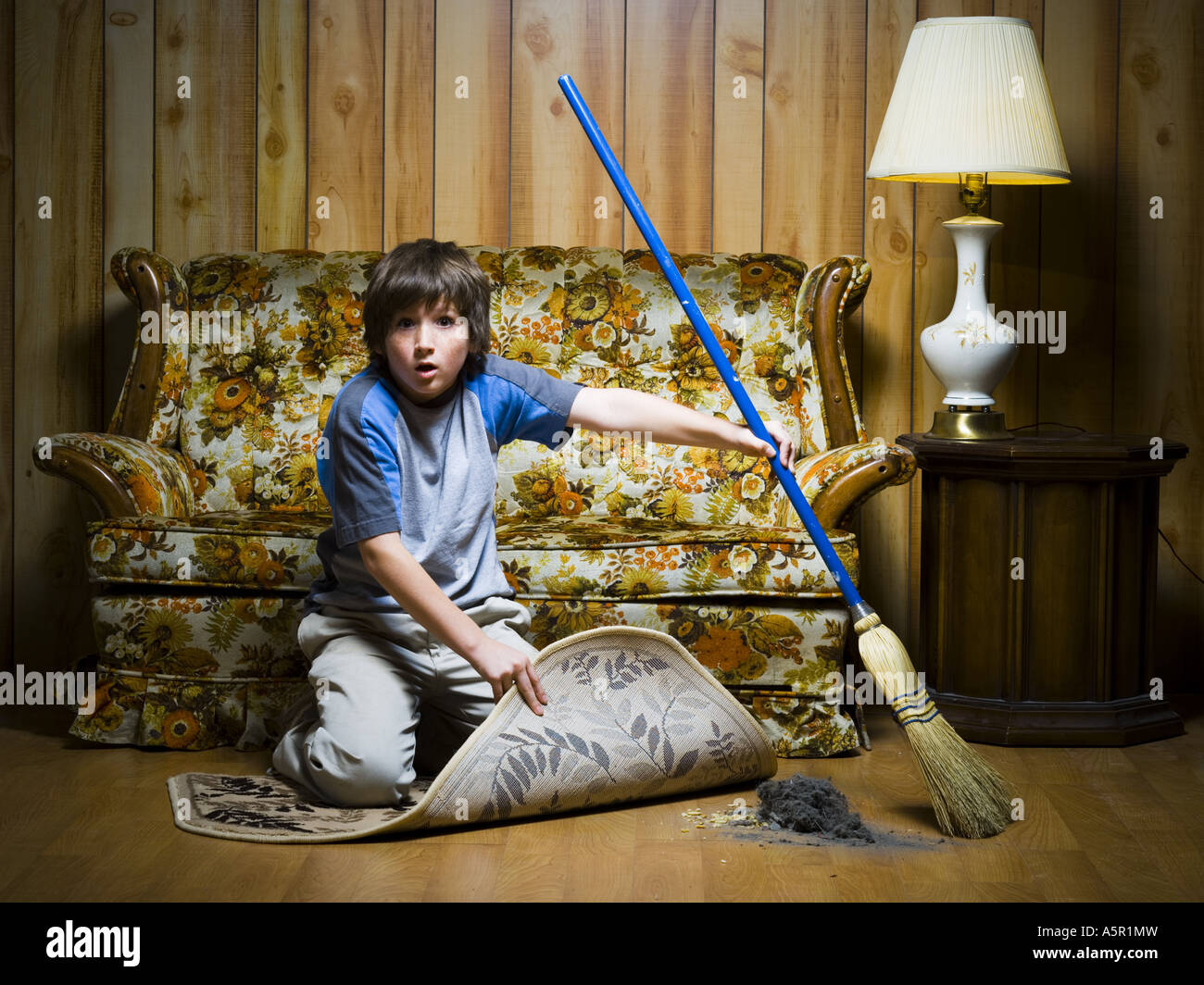 Boy sweeping dirt under rug Stock Photo Alamy