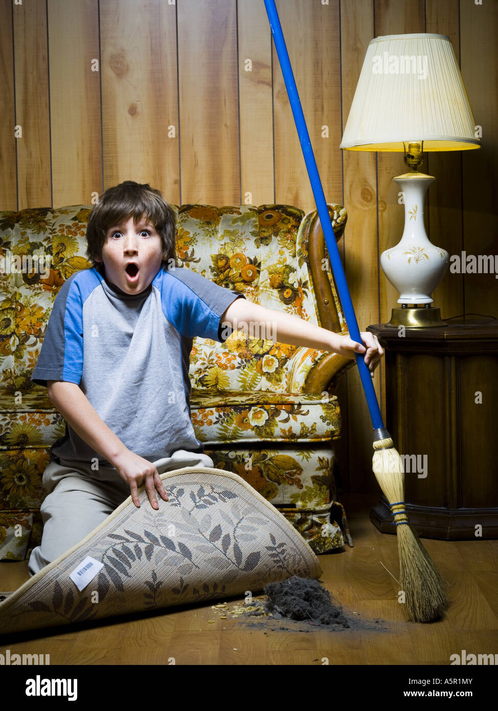 Boy sweeping dirt under rug Stock Photo Alamy