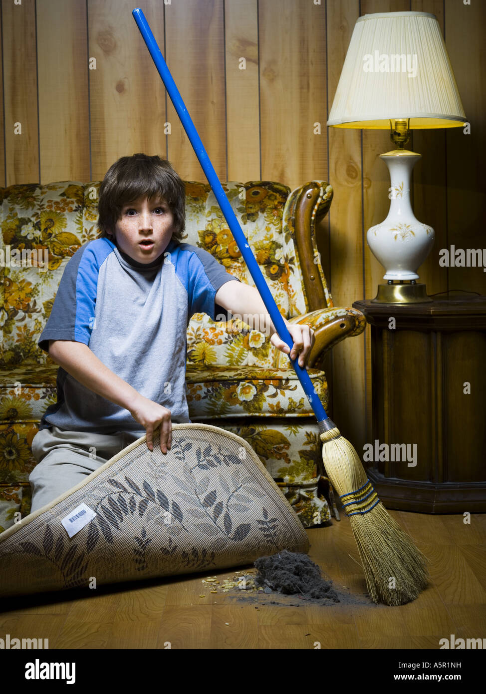 Boy sweeping dirt under rug Stock Photo Alamy
