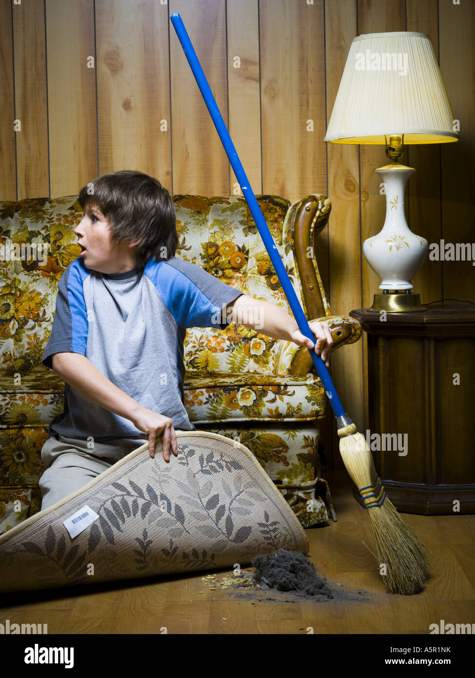 Boy sweeping dirt under rug Stock Photo Alamy