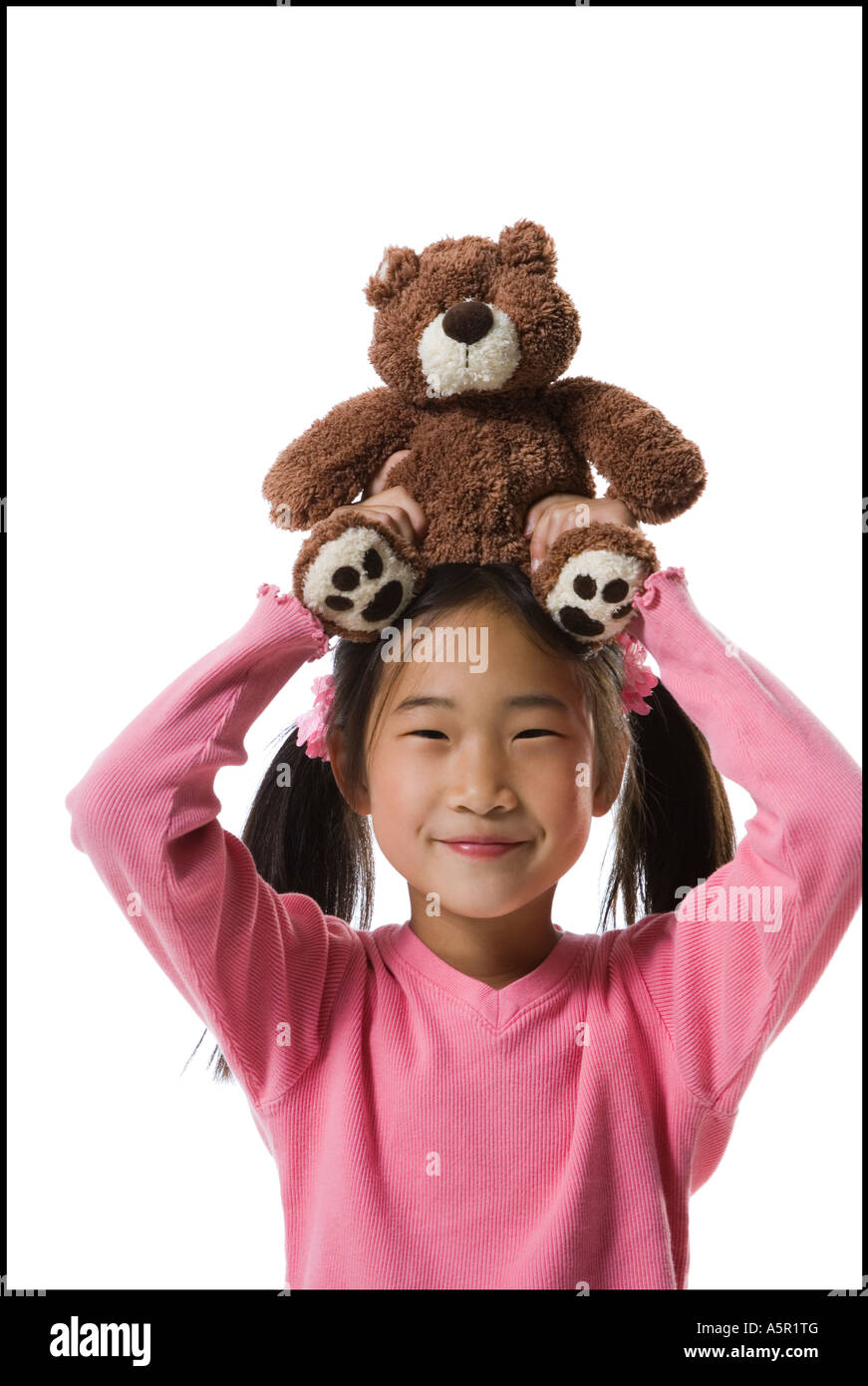 Portrait of a girl holding a teddy bear over her head and smiling Stock Photo