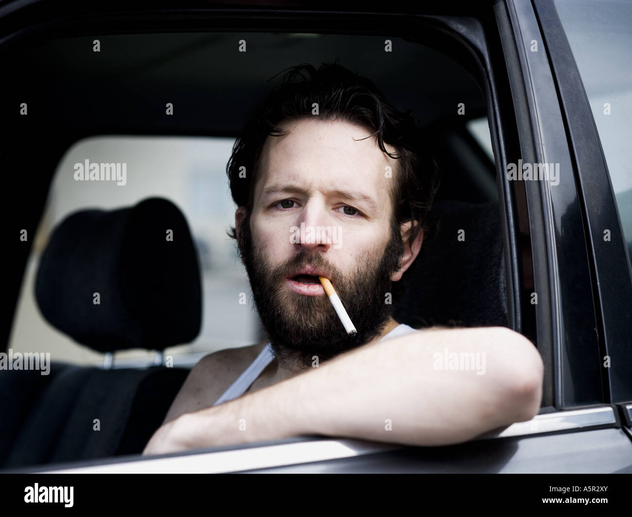 cigarette hanging out of mouth Man in car with cigarette hanging from mouth Stock Photo