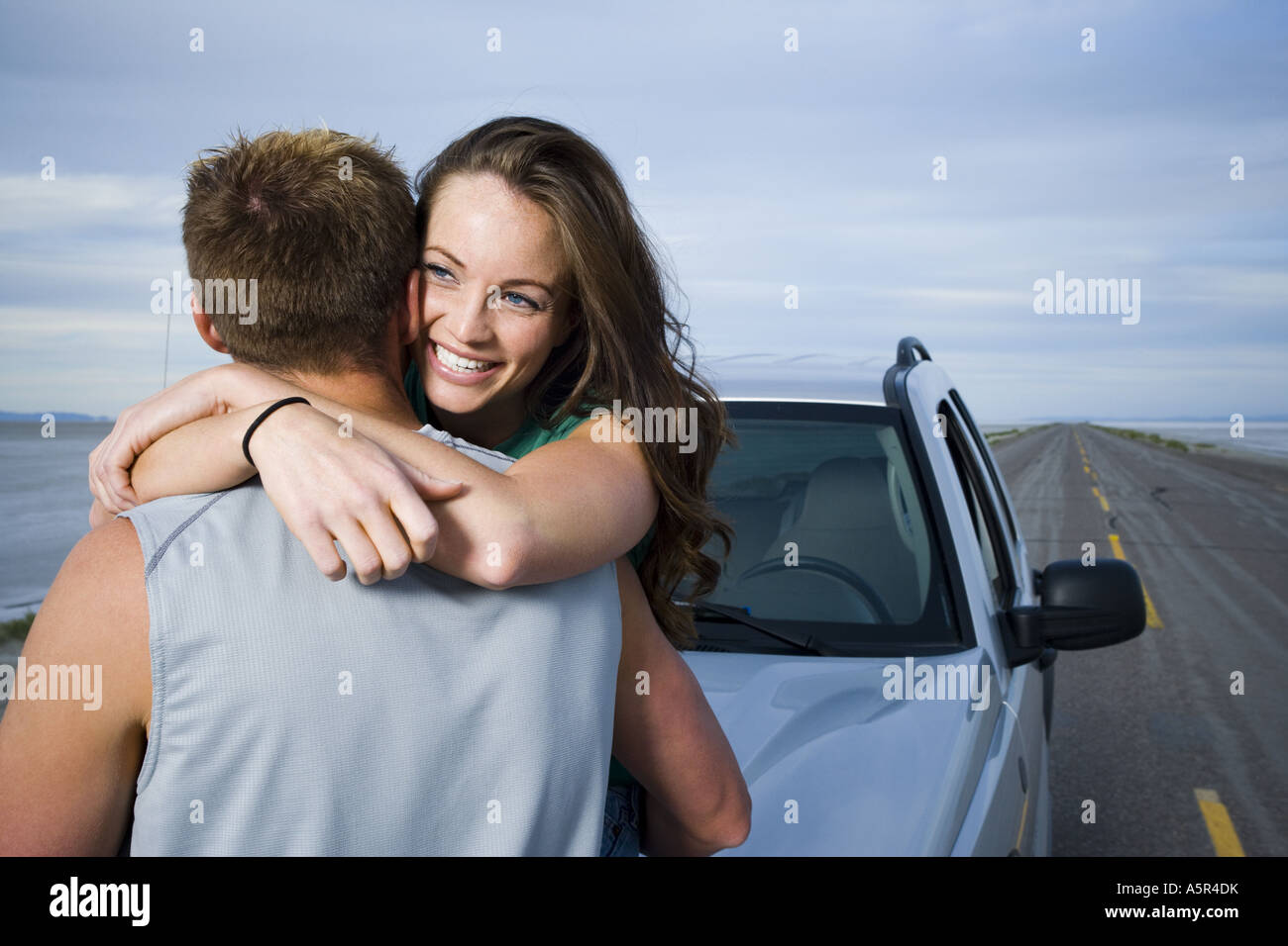 Rear view of a mid adult man and a young woman embracing each other ...