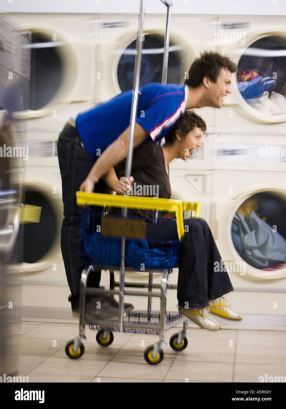 Young couple on trolley at Laundromat having fun Stock Photo - Alamy
