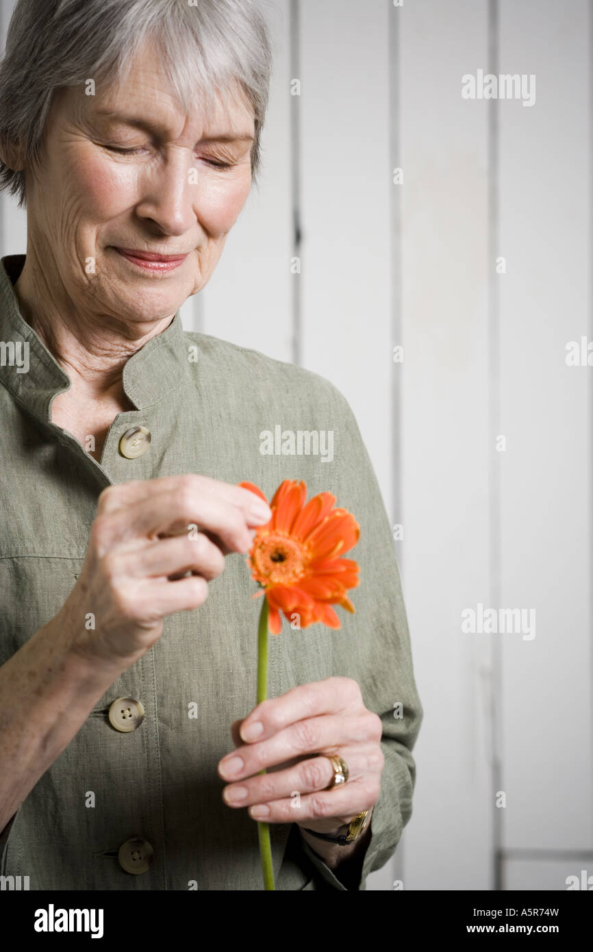 Portrait of an elderly woman holding a flower Stock Photo - Alamy