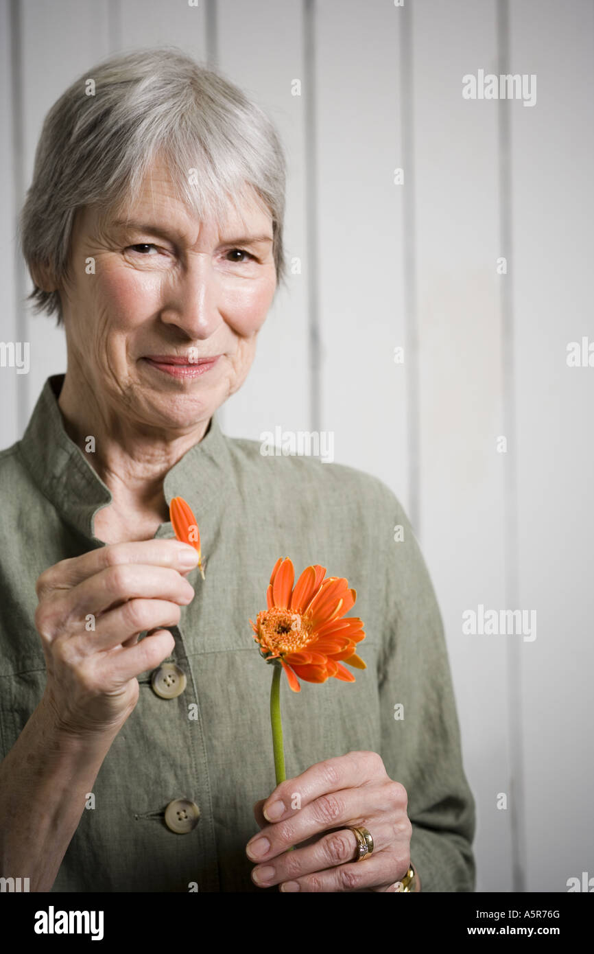 Portrait of an elderly woman holding a flower Stock Photo - Alamy