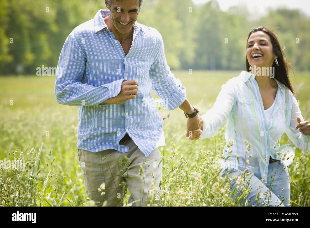 man and a woman holding hands and running in a field Stock Photo - Alamy