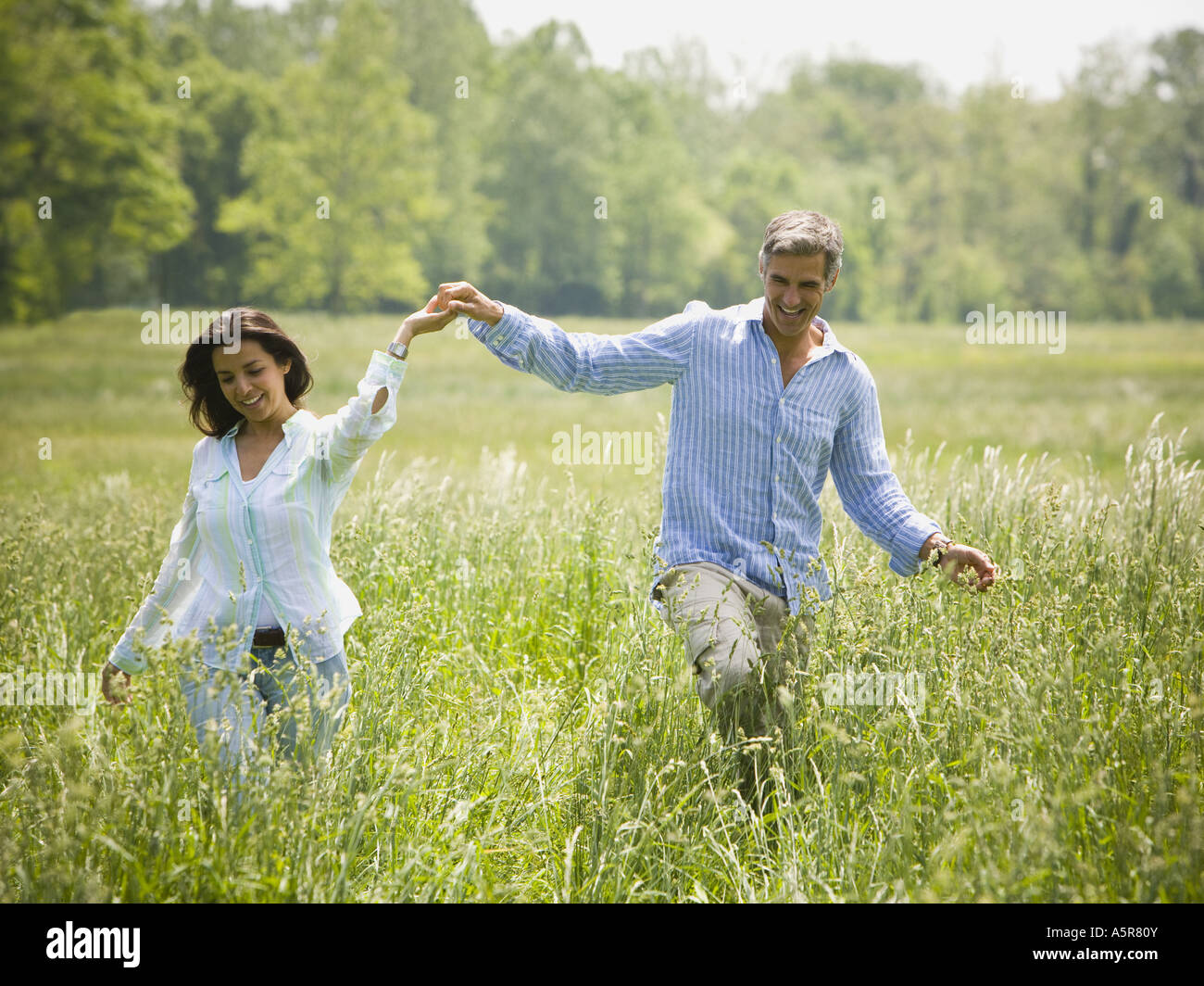 man and a woman holding hands and running in a field Stock Photo - Alamy