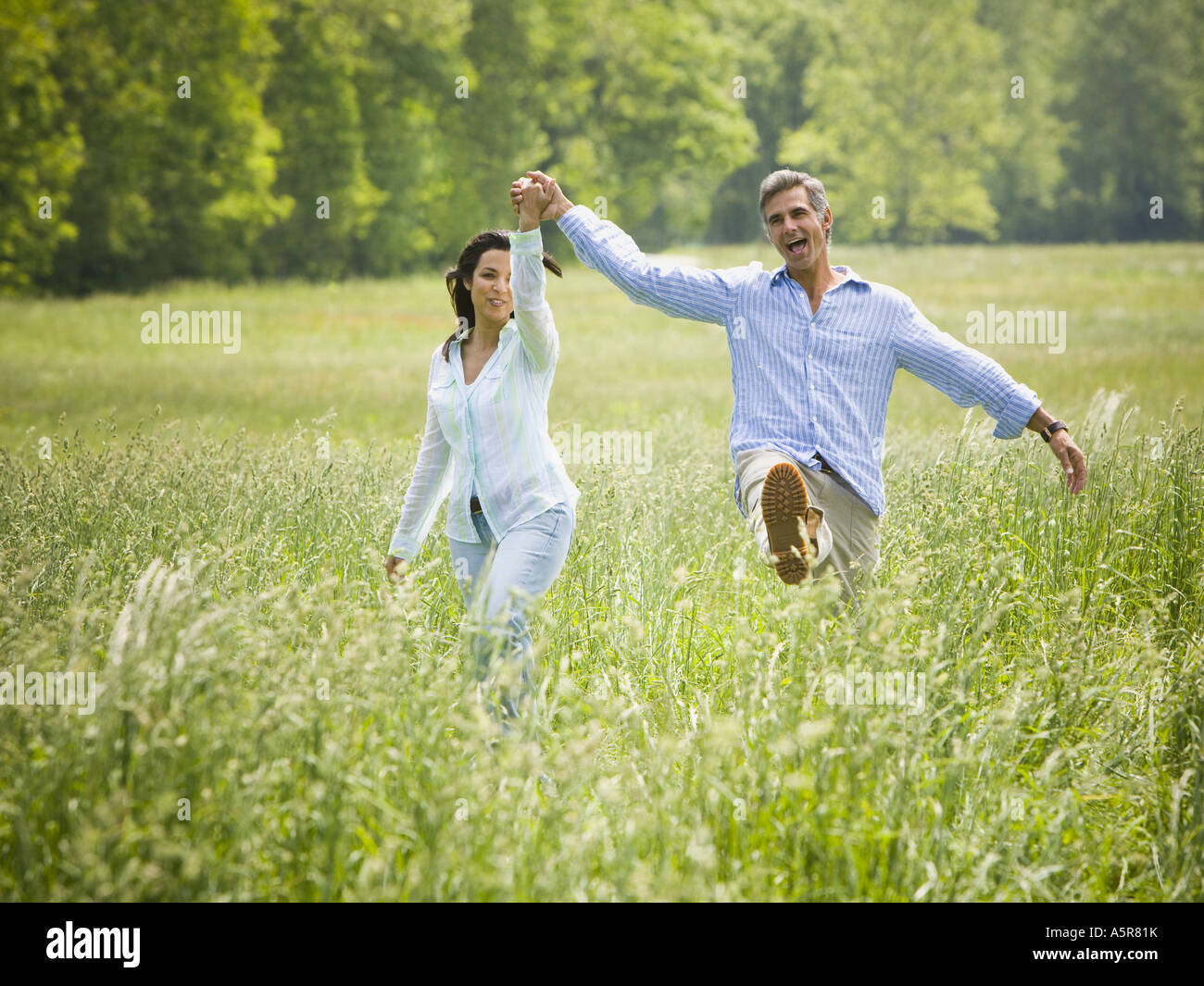man and a woman holding hands and running in a field Stock Photo - Alamy