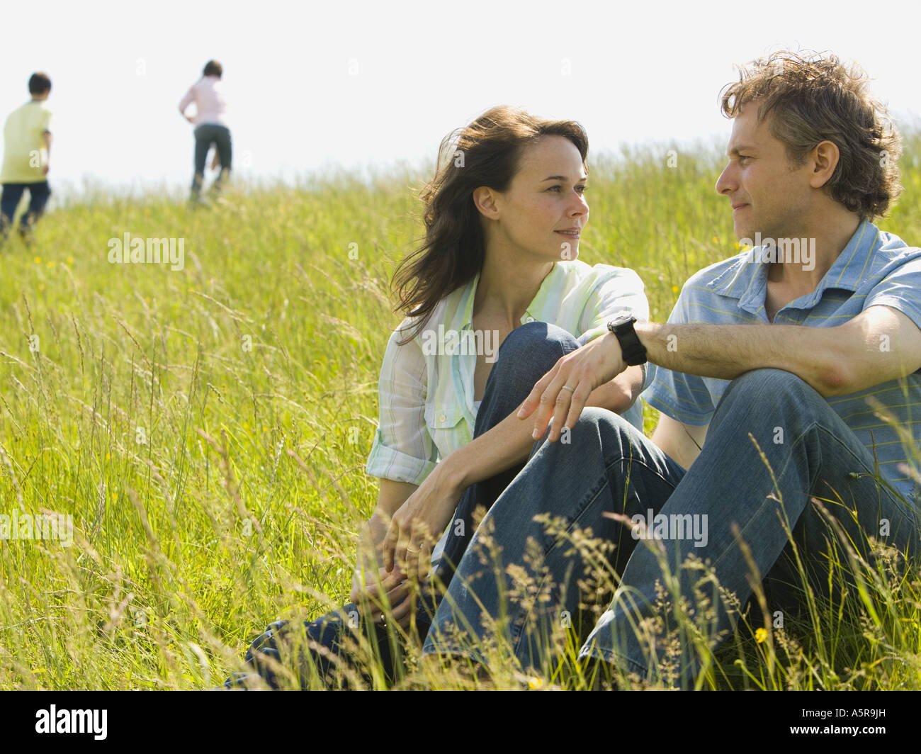 Close up of a woman and a man sitting together and laughing in a field ...